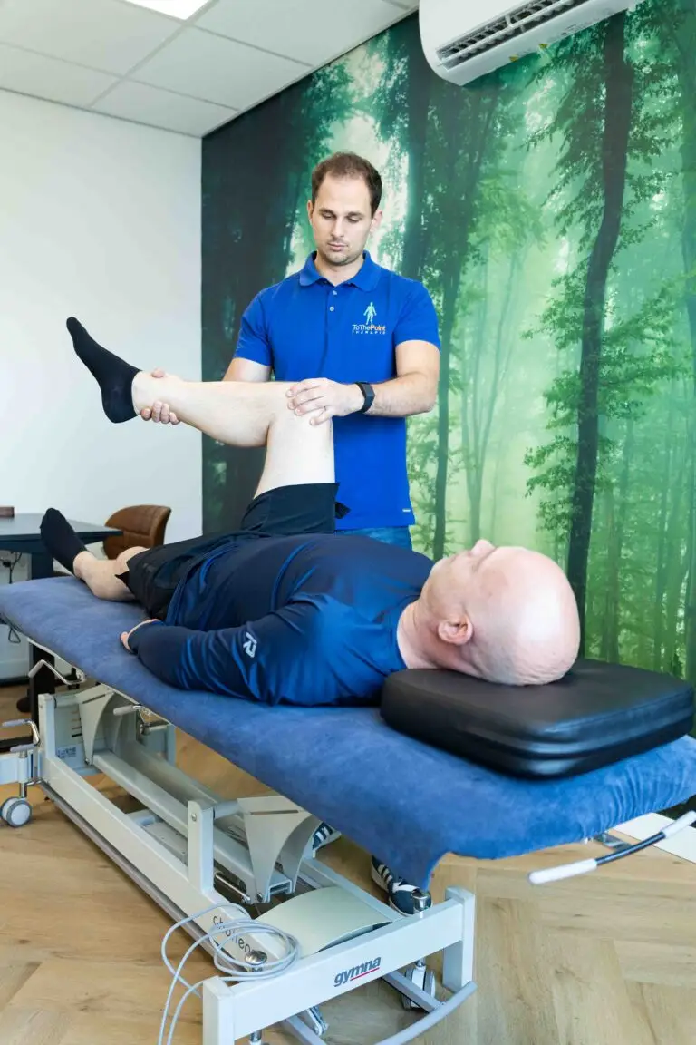 Fysiotherapeut voert een mobiliteitstest uit op het been van een patiënt in een behandelkamer met een rustgevend bosdecor.